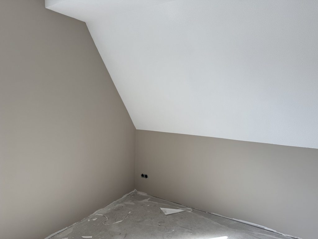 Zolderkamer met een schuine wand en egaal afgewerkte wanden in een warme grijstint