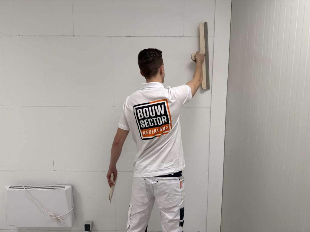 Stukadoor van Bouwsector Nederland trekt een wand glad met een lange spaan